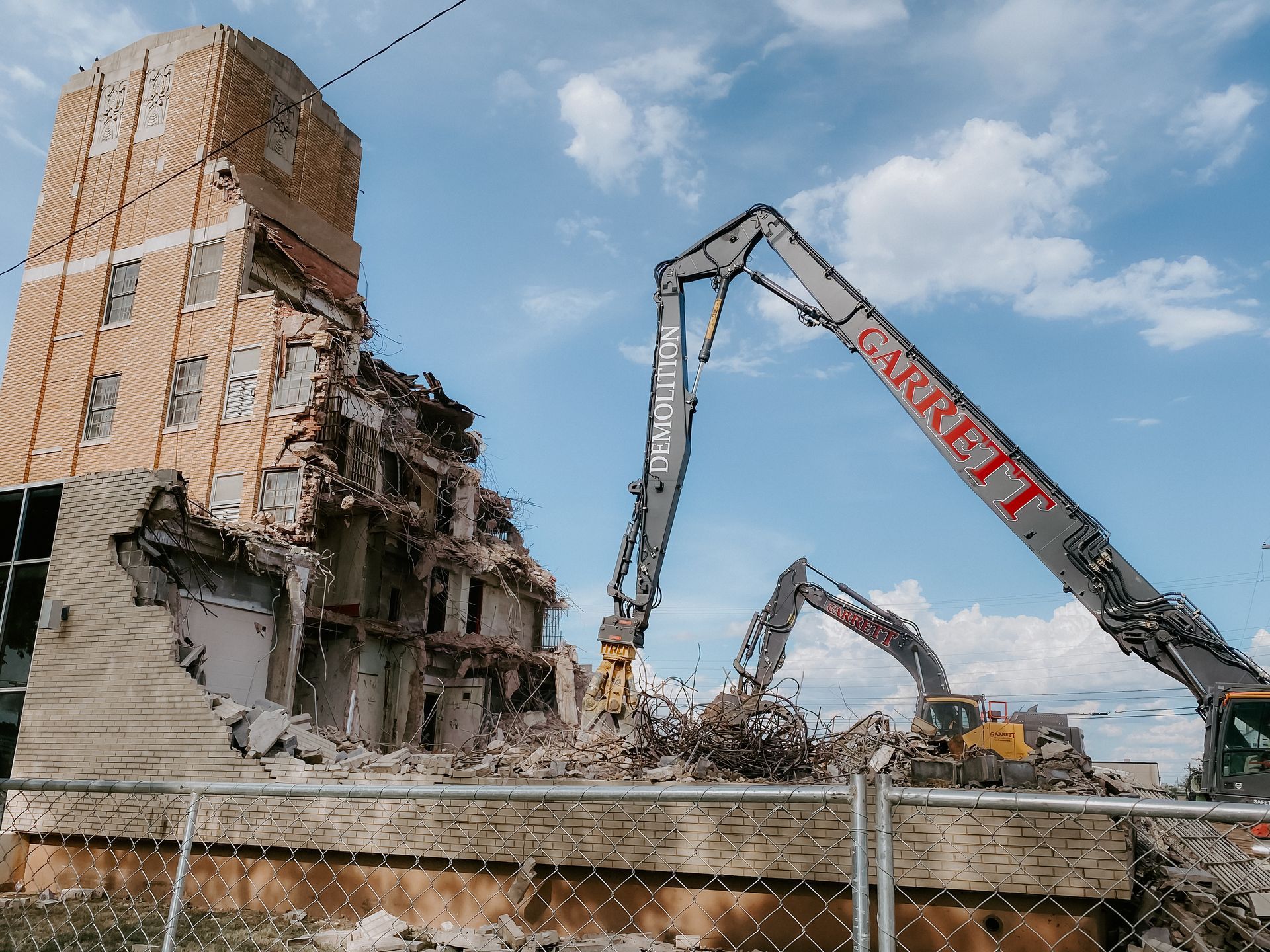 A large building is being demolished by a large crane.