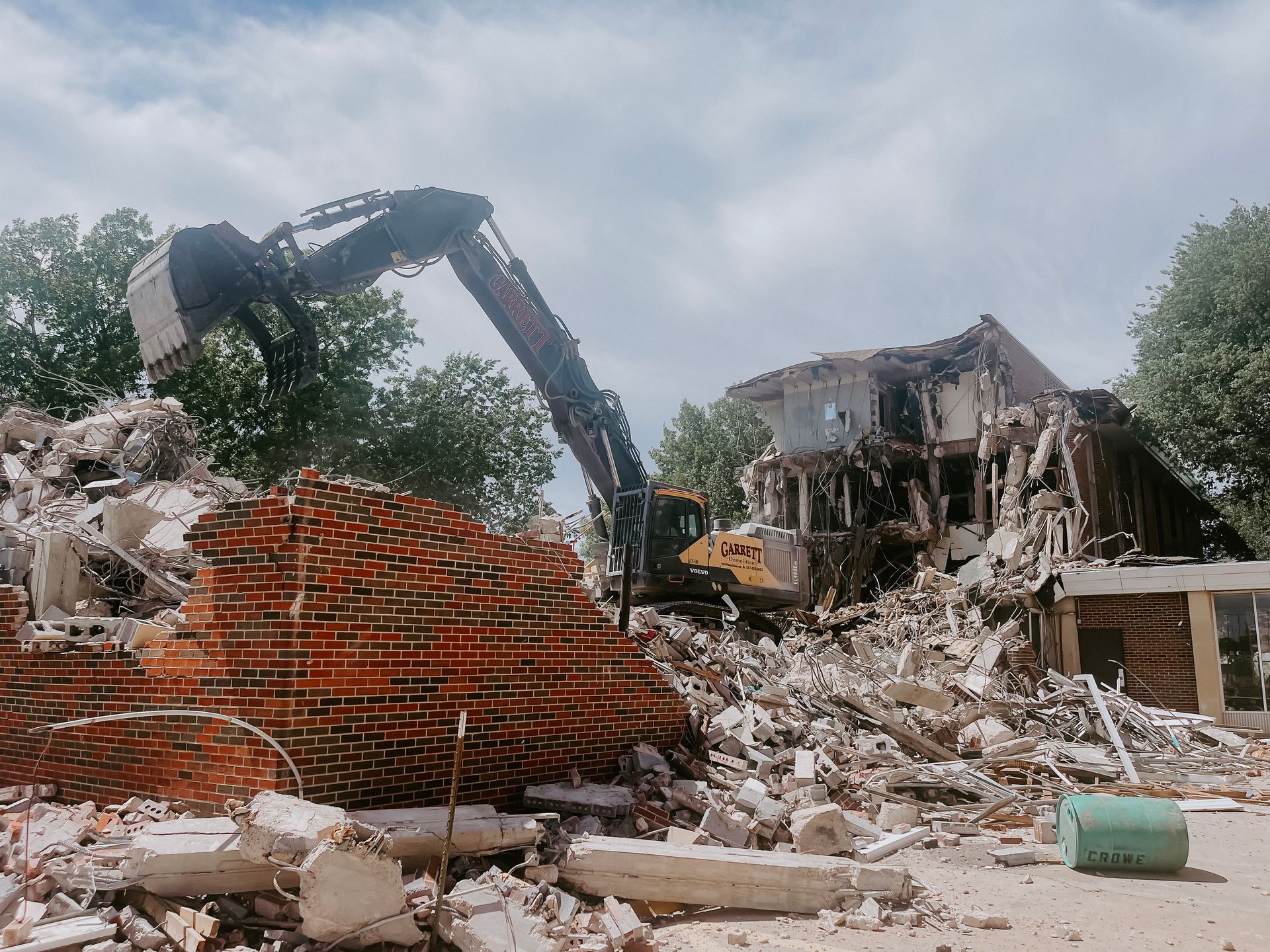 A large brick building is being demolished by a bulldozer.