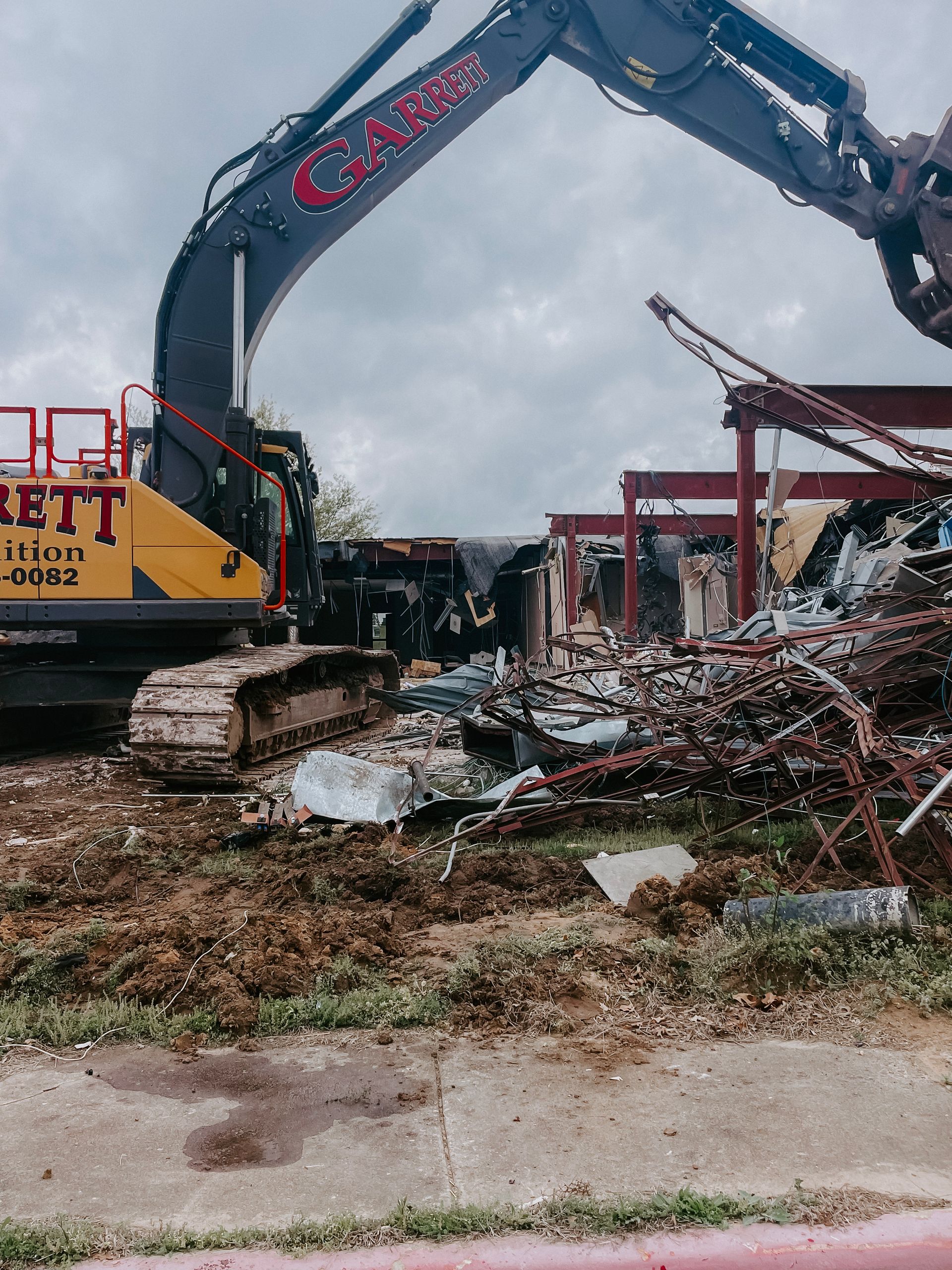 A bulldozer is demolishing a building in a parking lot.