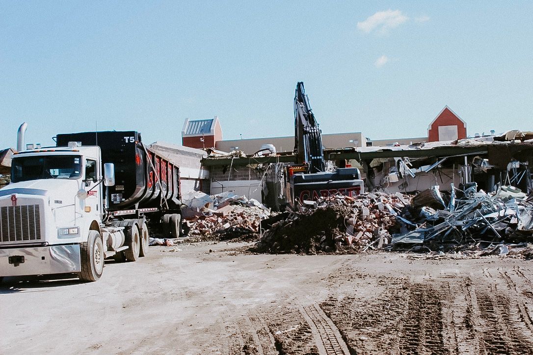 A large excavator is demolishing a brick building.