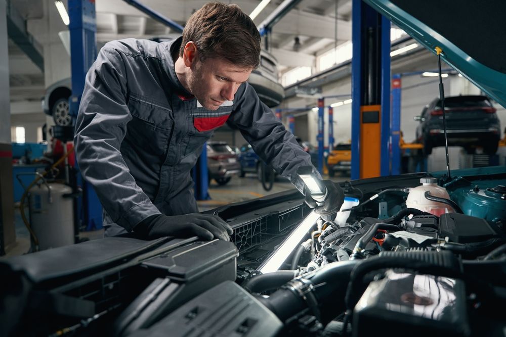 A man is working on the engine of a car in a garage.