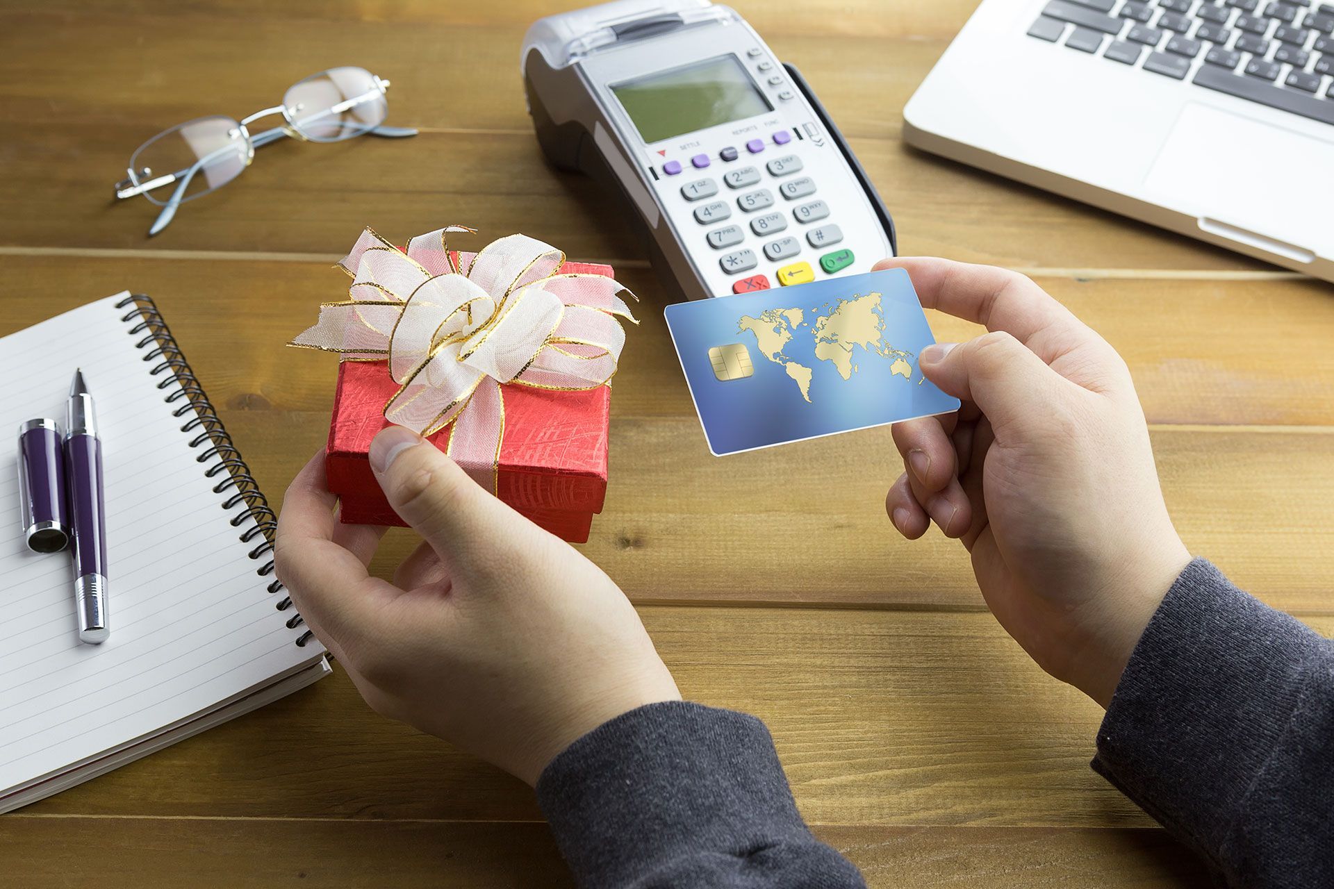 A person is holding a gift box and a credit card.