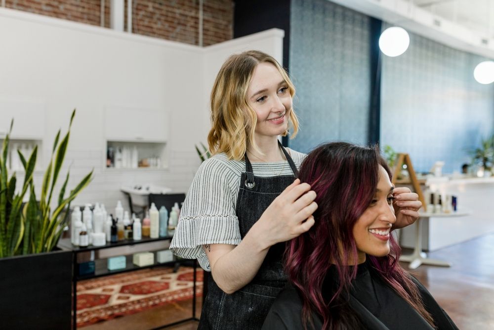 A woman is getting her hair cut by a hairdresser in a salon.