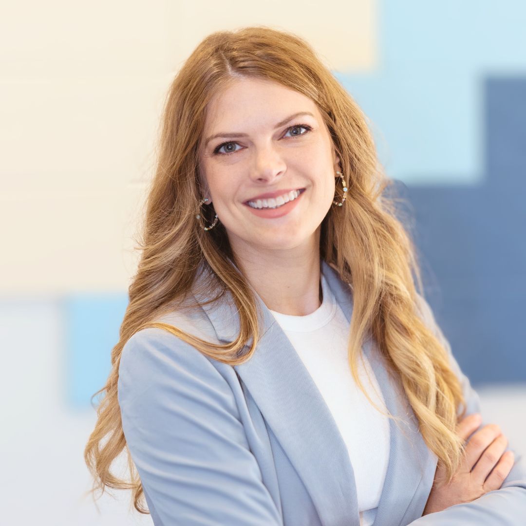 a woman in a blue jacket and white shirt is smiling a Brainspotting therapist in Texas.