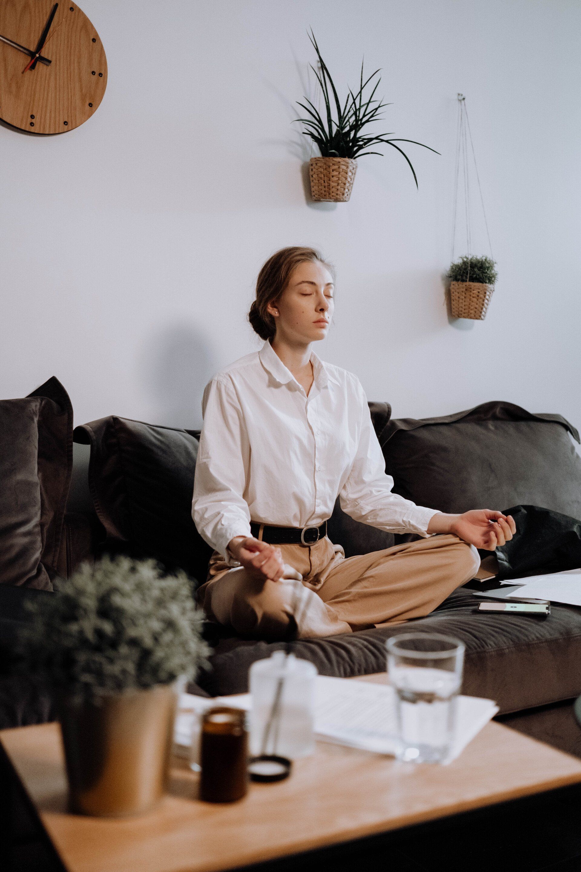 a woman sits on a couch meditating with her eyes closed listening to healing frequencies that deepen meditation in Grapevine Texas