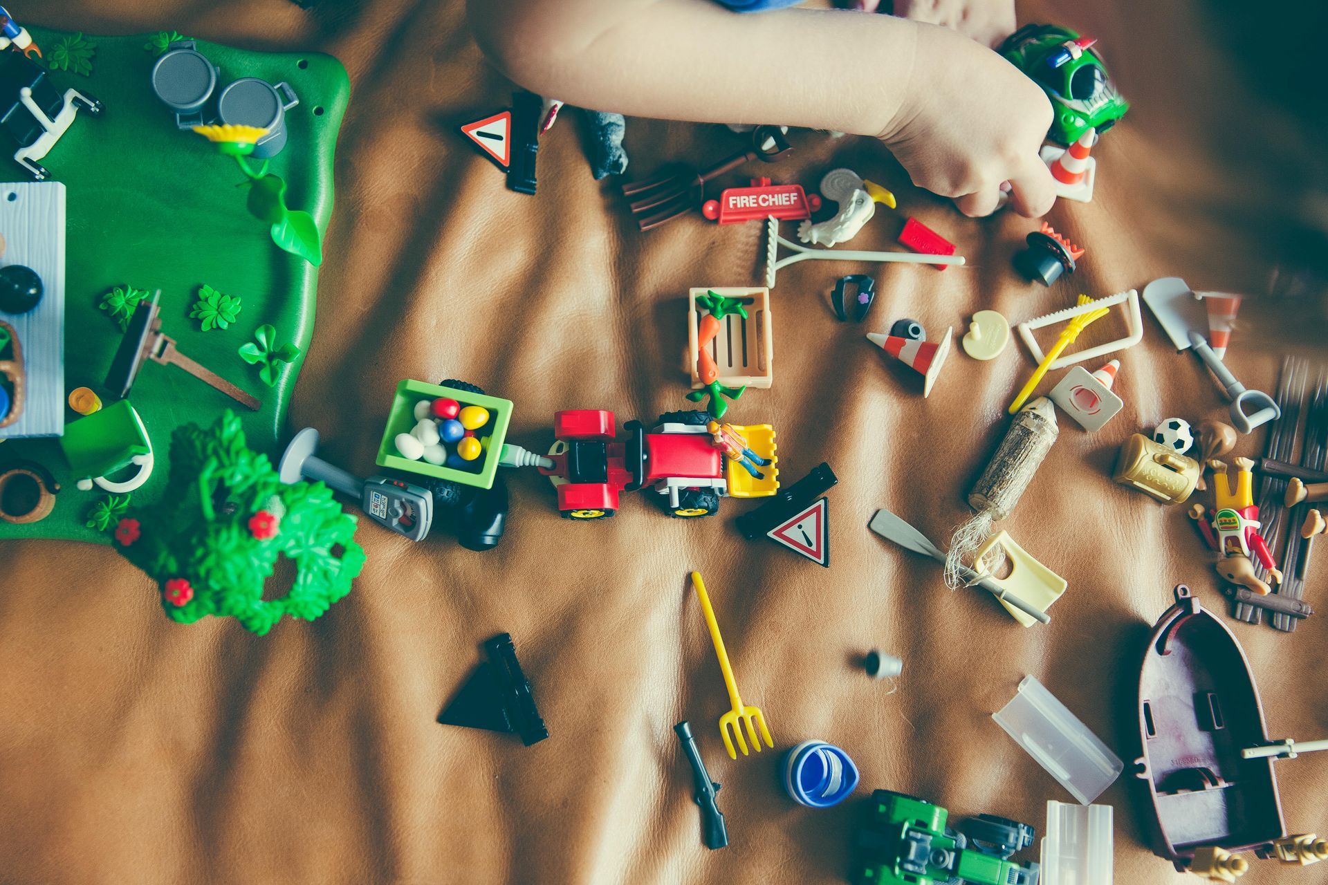A child is playing with a bunch of toys on a bed receiving treatment for ADHD in DFW