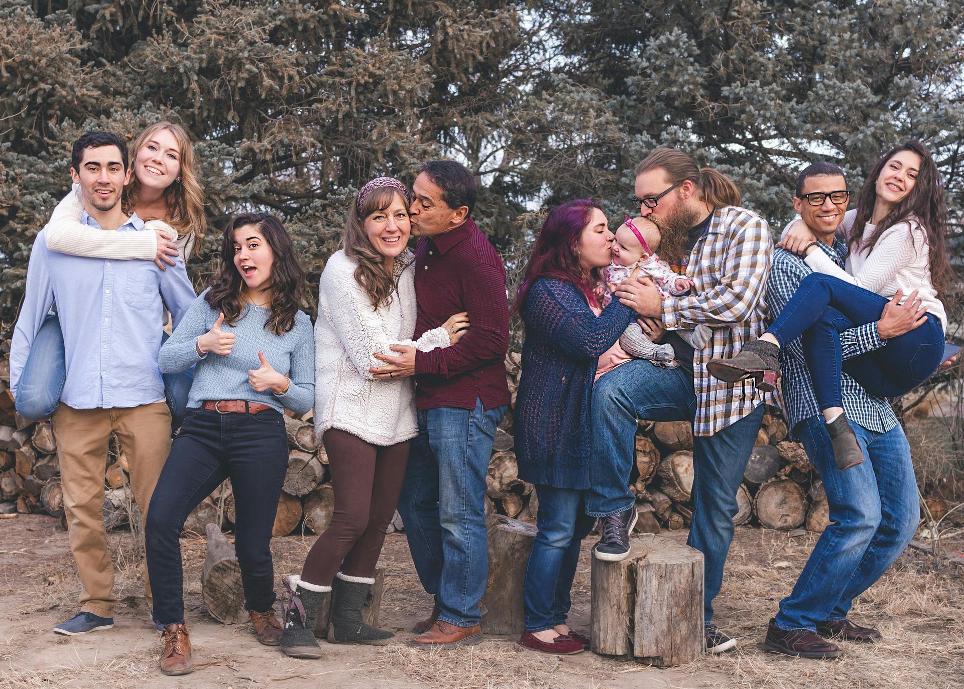 A group of people are posing for a picture in front of a pile of logs attended blended family counseling in Grapevine, TX.