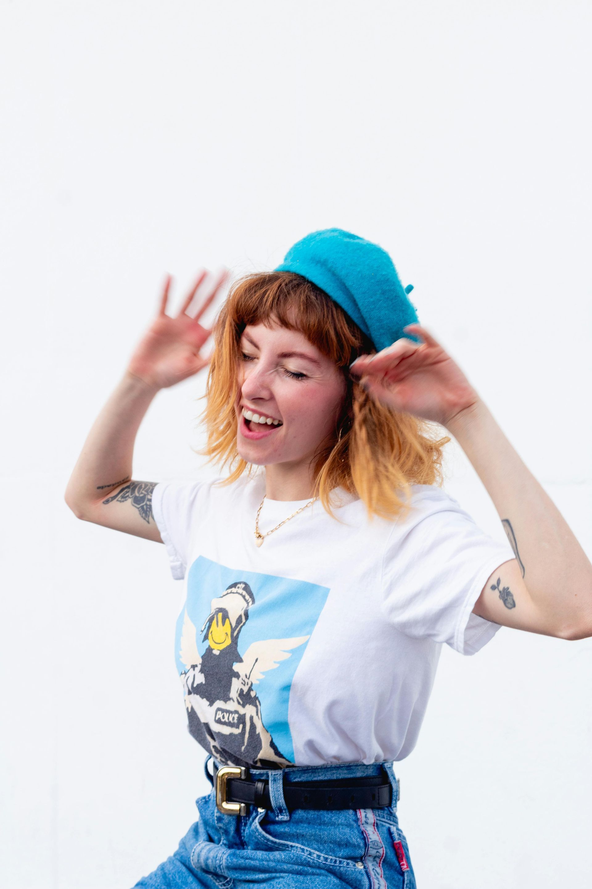 A woman wearing a white t-shirt and a blue hat is making a funny face.