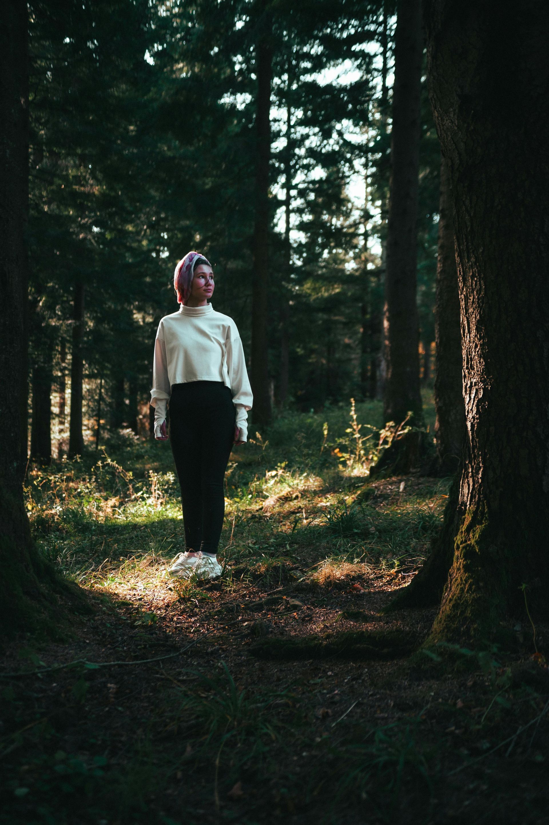 A woman is standing in the middle of a forest participating in a weekend counseling intensive in Grapevine Texas.