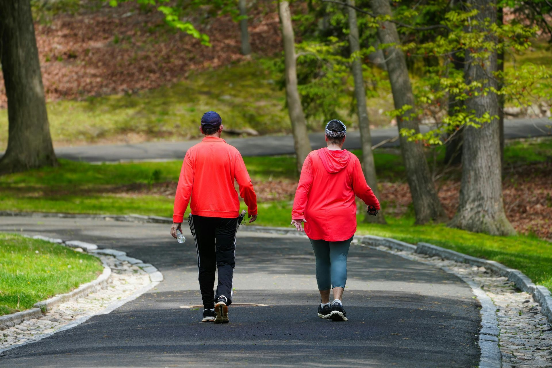 Two people in red jackets walking on a curving park path to regulate nervous system and reduce anxiety