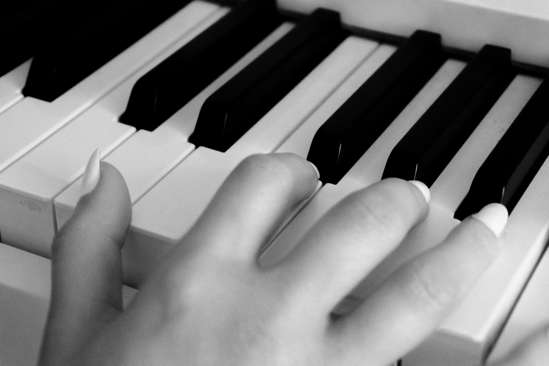 Hand playing piano keys in black and white close-up to cope with anxiety.