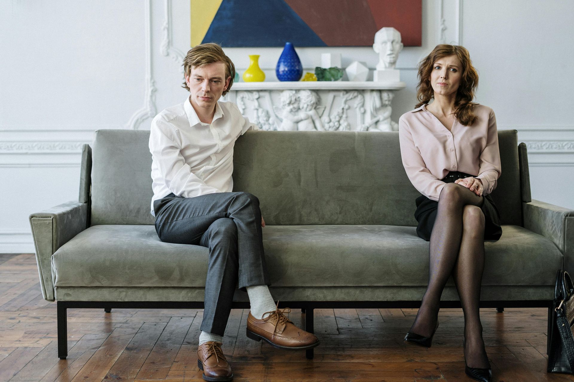 A man and a woman are sitting on a couch looking at each other attending marriage counseling in Dallas-Fort Worth