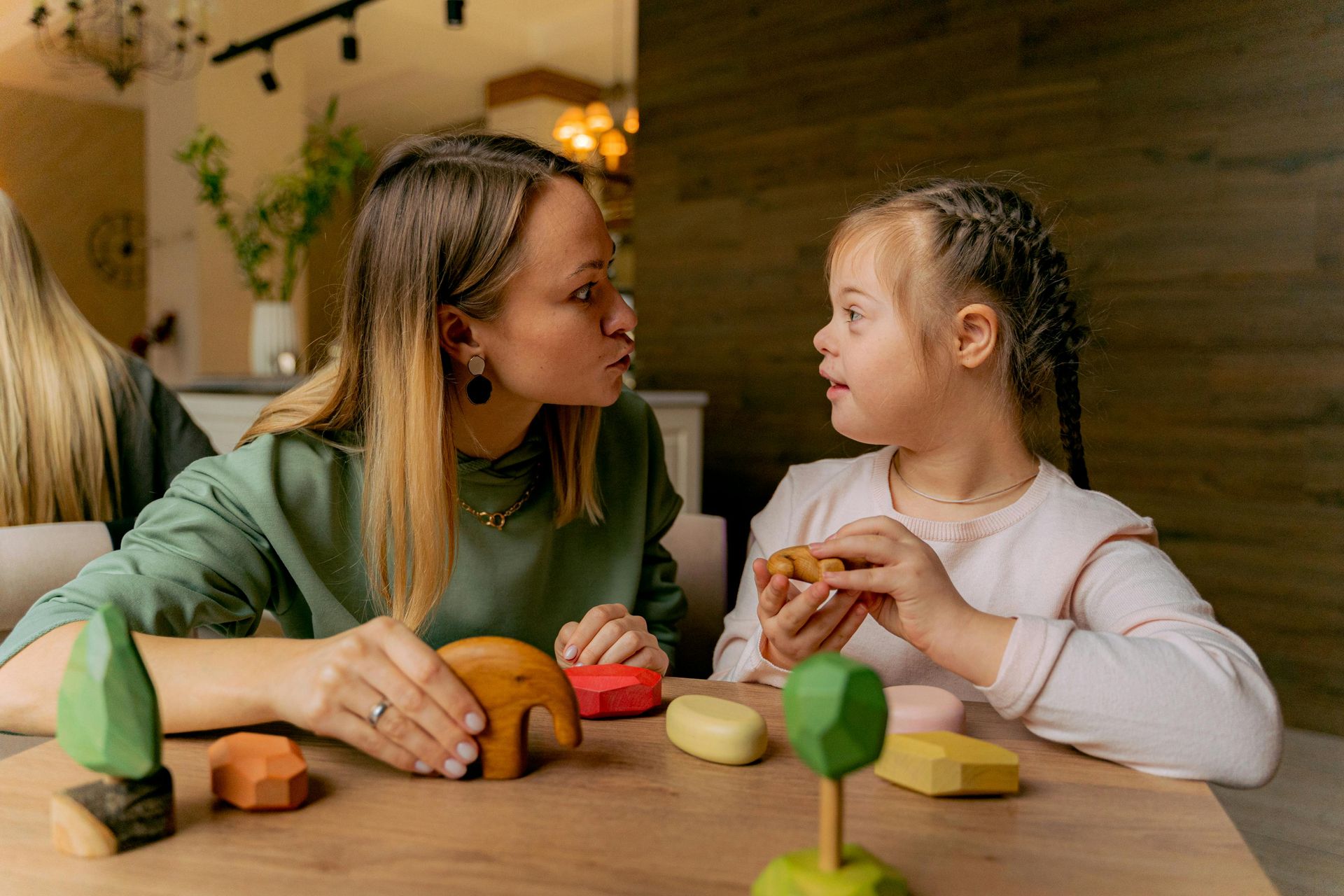 A woman and a little girl are sitting at a table playing with toys participating in child therapy in Grapevine Texas