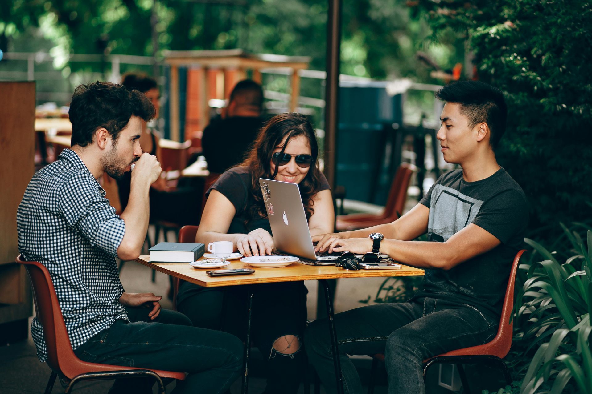A group of people are sitting at a table with laptops.