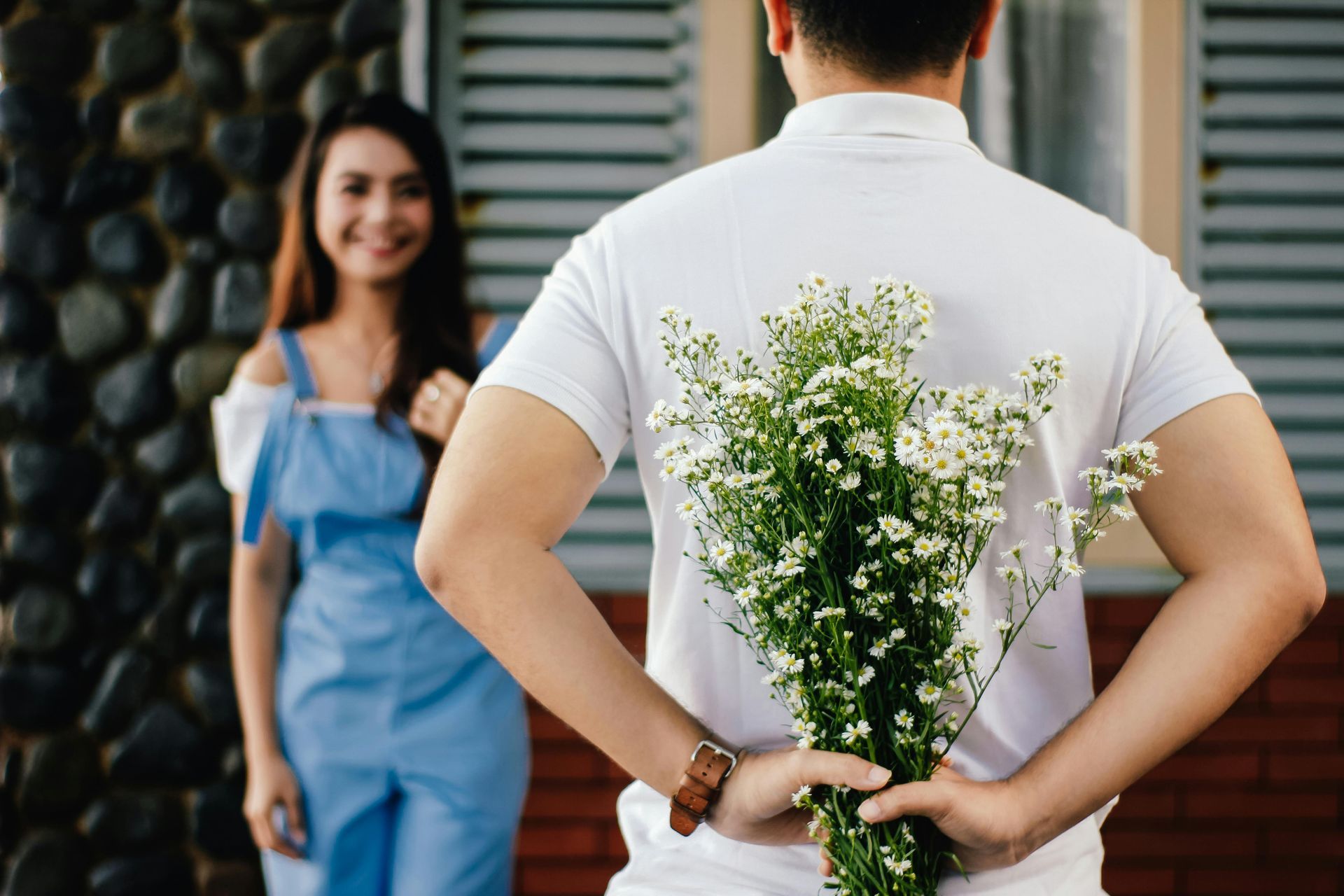 A man is holding a bouquet of flowers behind his back for marriage enrichment in Dallas.