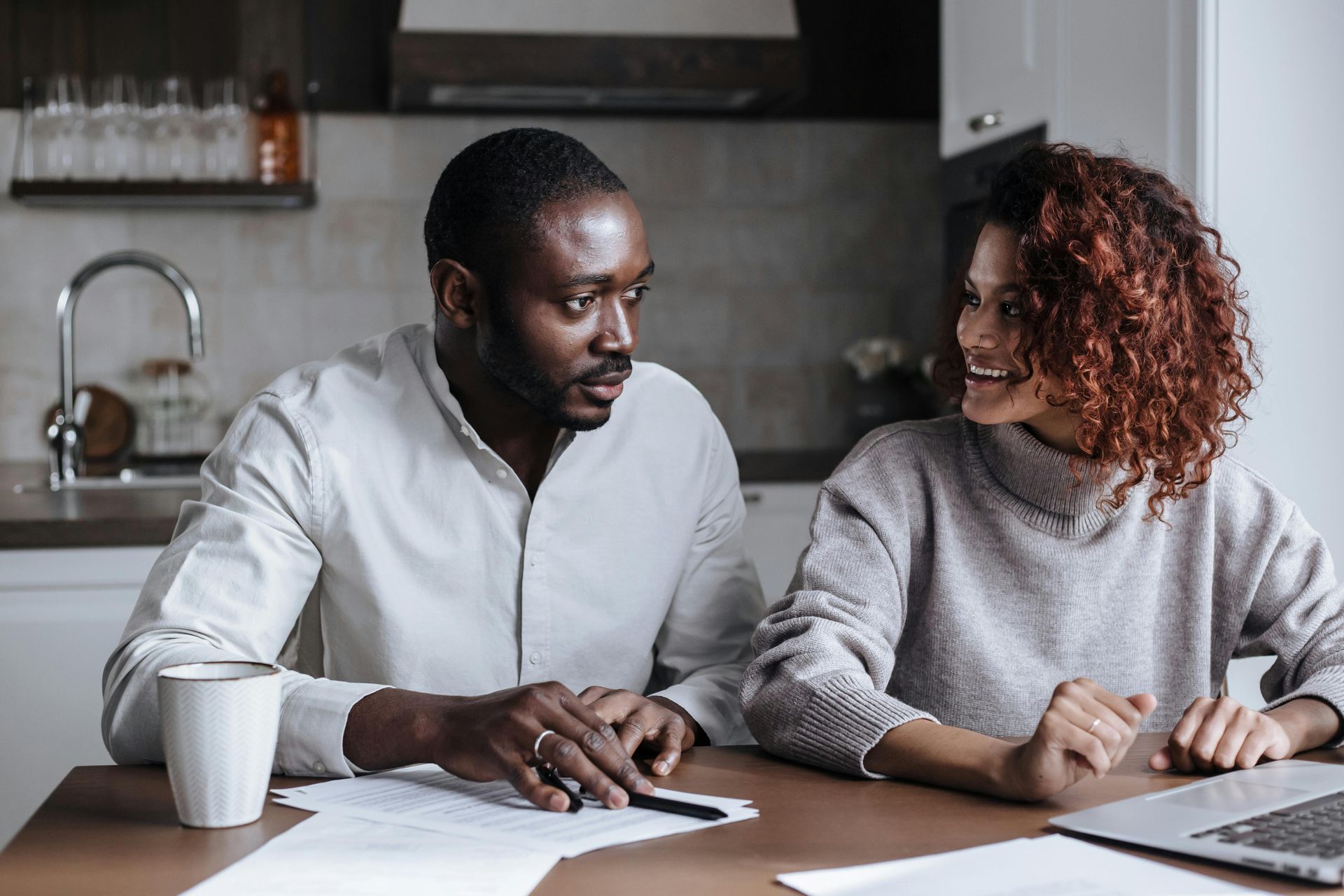 A man and a woman are sitting at a table with papers and a laptop going over options for divorce discernment in DFW.