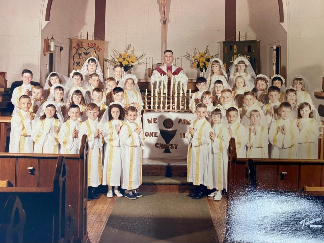 Children in white robes posing on church altar during a communion ceremony