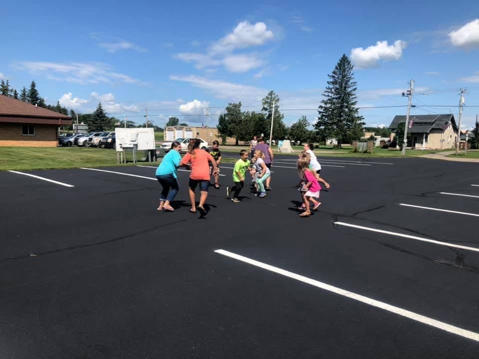 Children running together in a parking lot on a sunny day
