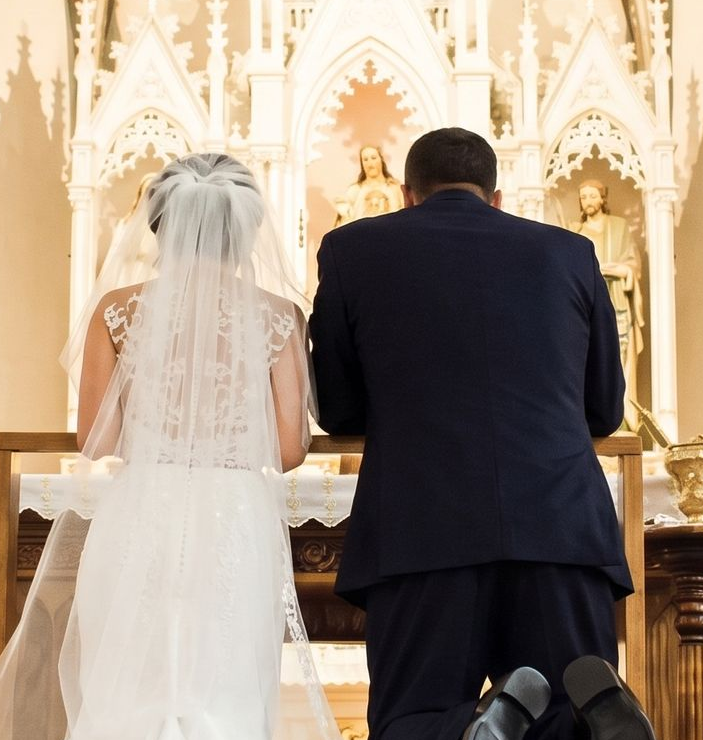 Bride and groom kneeling at an altar during a wedding ceremony in a church