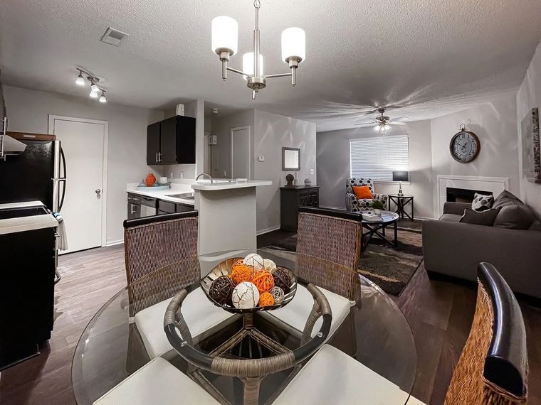 Open-concept living area with kitchen, dining table, and gray seating.