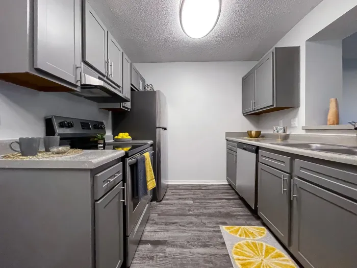Gray galley kitchen with cabinets, appliances, and yellow accents.