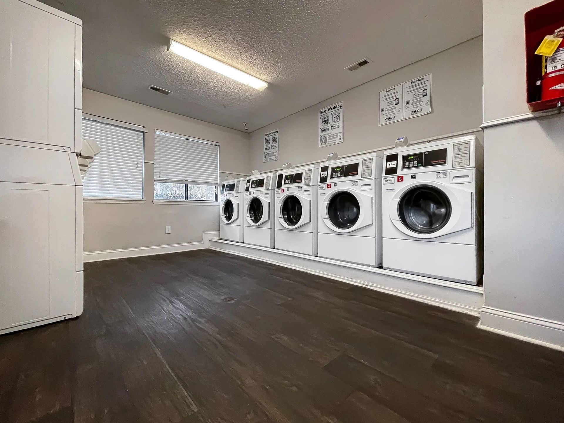 Common laundry room with a row of front-loading washing machines against the wall.