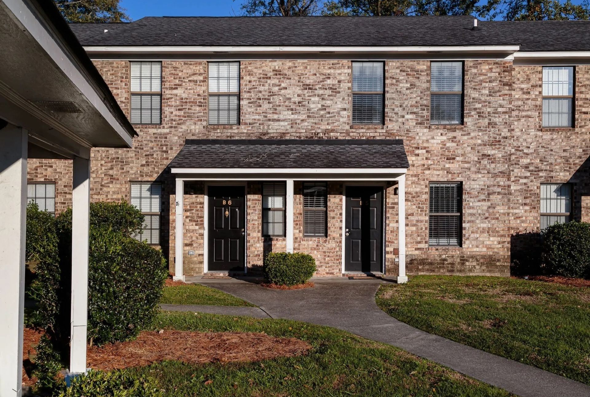 Brick exterior of a two-unit apartment building with a shared covered entry.