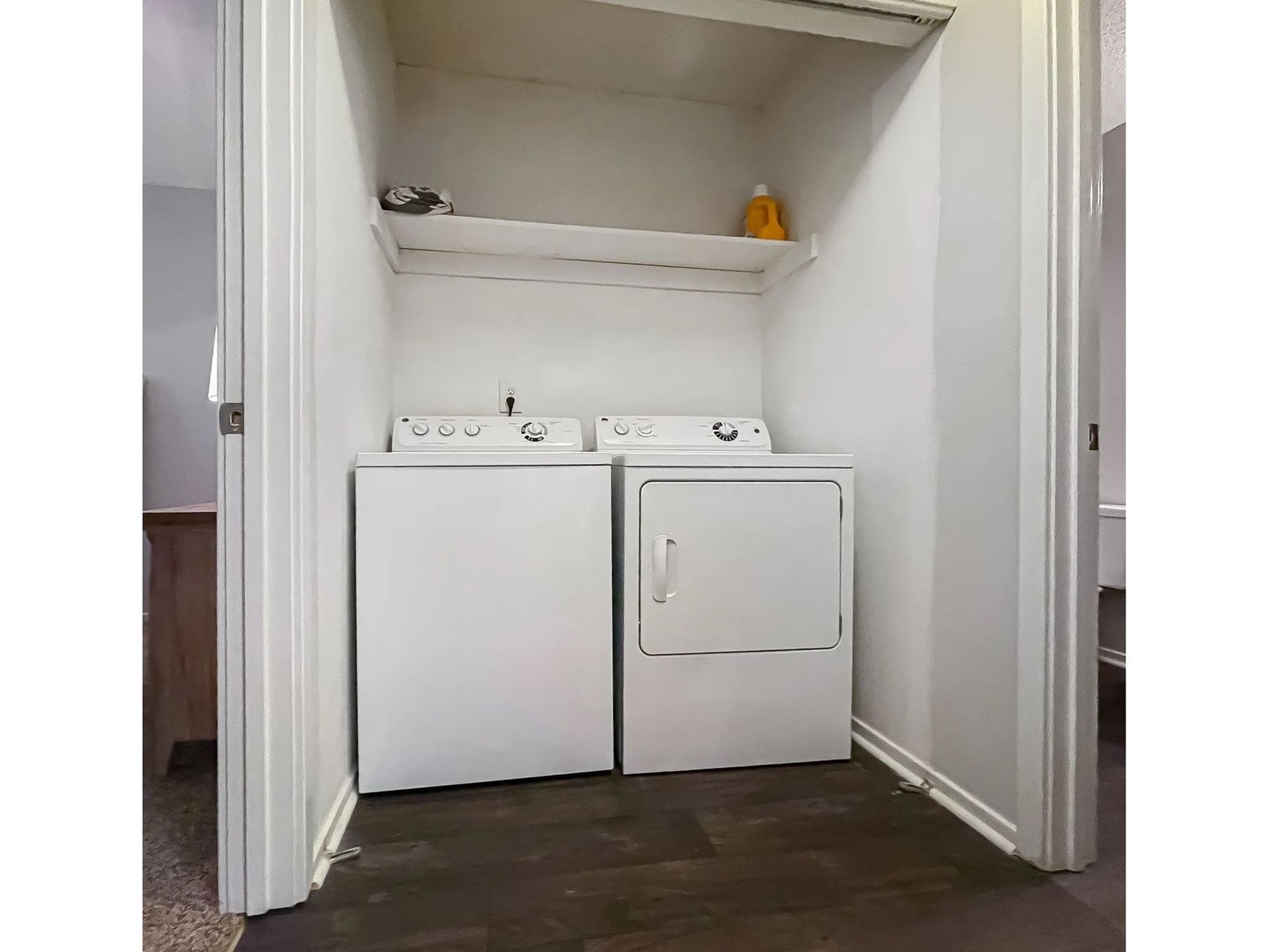 White washer and dryer in a small laundry closet with a shelf above.