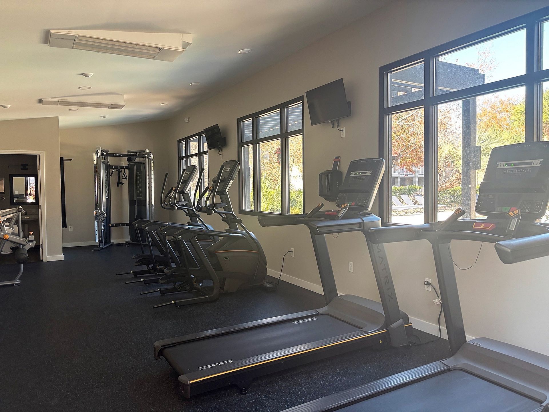 Bright on-site fitness center with treadmills and cardio machines along large windows.