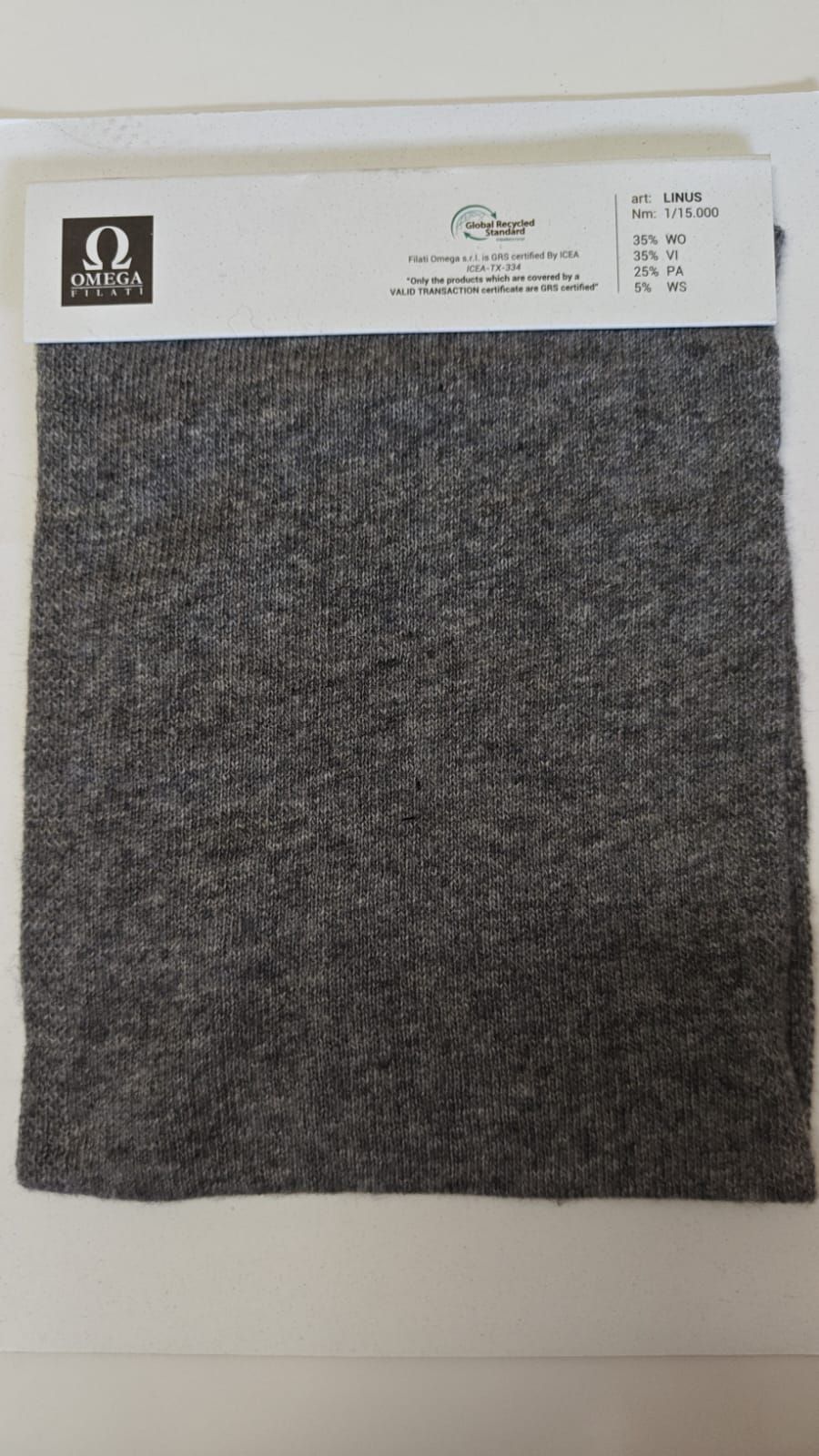 Muestra de tejido gris con etiqueta adjunta.