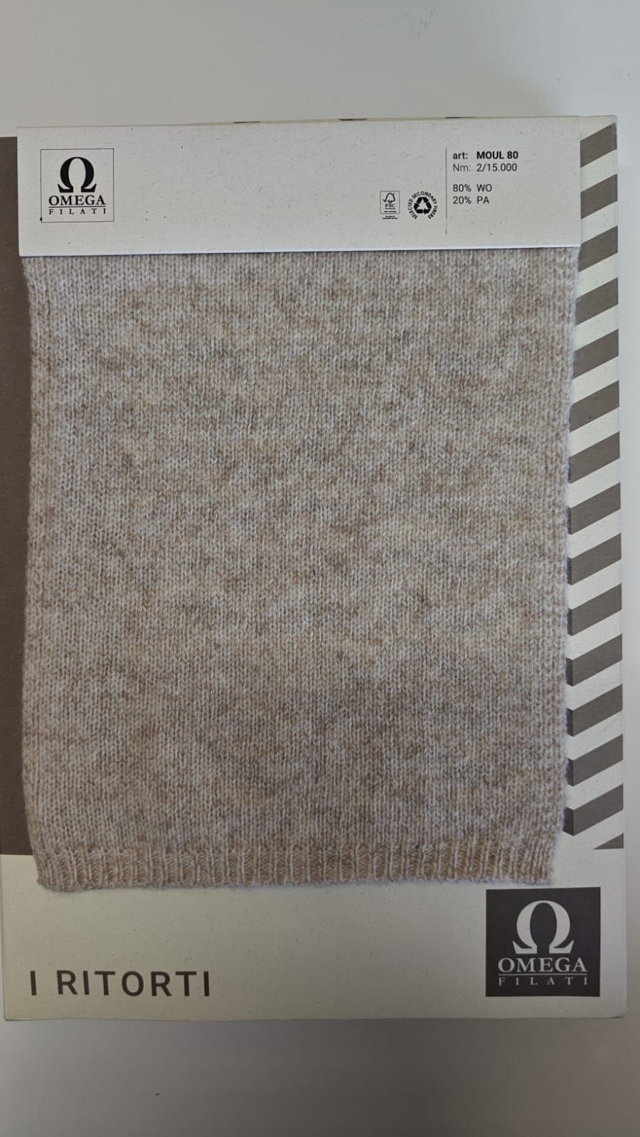 Muestra de tejido de punto, color beige, con una etiqueta que lleva el logotipo de 
