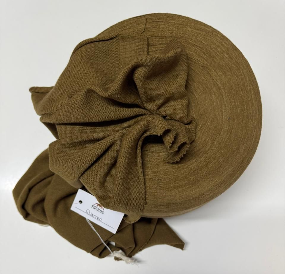 Carrete de tela verde oliva con drapeado plegado y etiqueta adjunta.