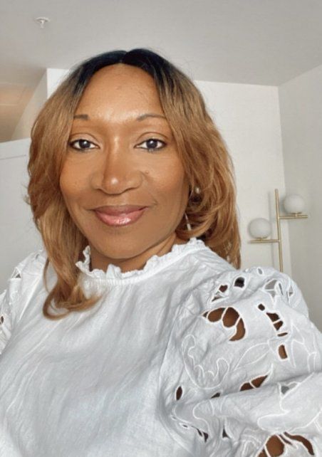Une femme porte une chemise blanche et sourit à la caméra.