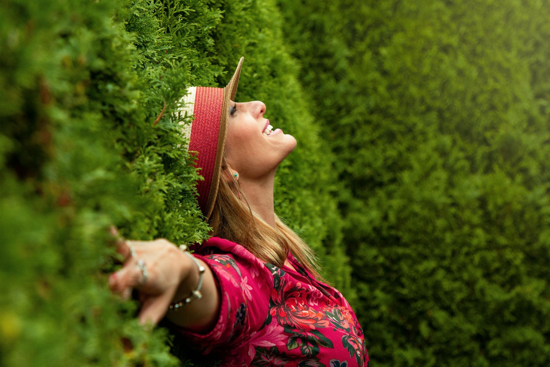 Une femme se tient à côté d'un buisson, les bras tendus.