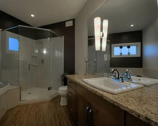 A bathroom with a sink , toilet , shower and mirror.