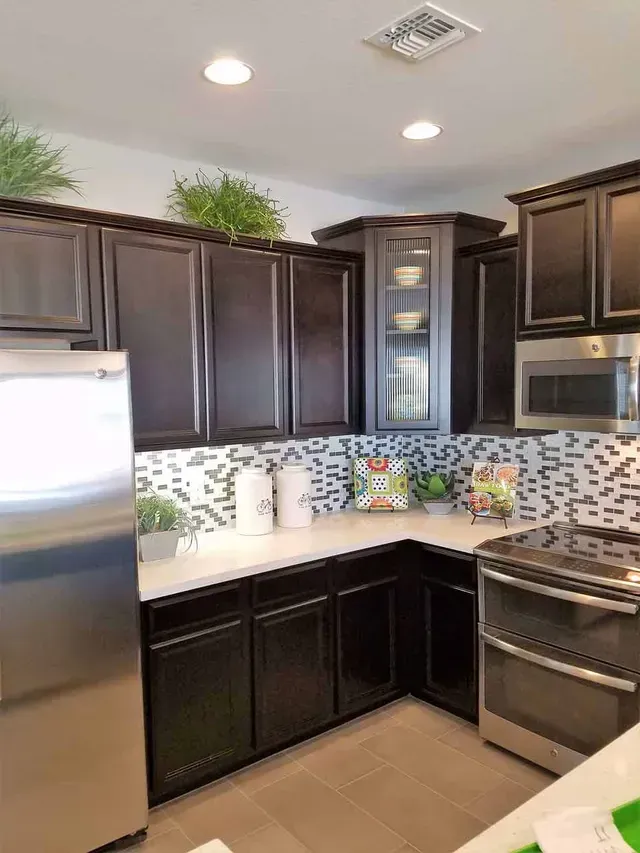 A kitchen with stainless steel appliances and black cabinets.