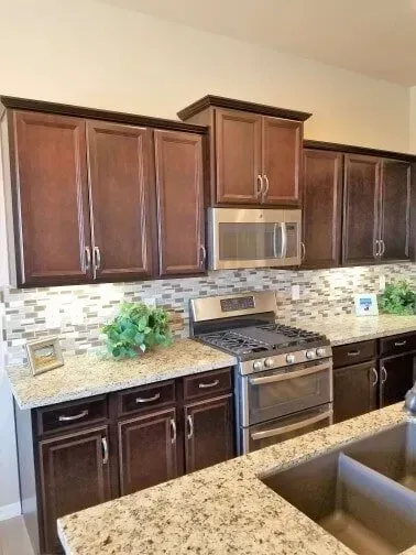 A kitchen with wooden cabinets, stainless steel appliances, granite countertops, and a sink.