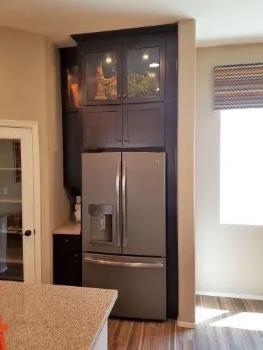 A kitchen with a refrigerator and cabinets built into the wall.