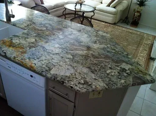 A kitchen with a granite counter top and a dishwasher.