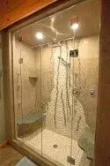A bathroom with a walk in shower with sliding glass doors.