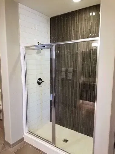 A bathroom with a walk in shower with a glass door.