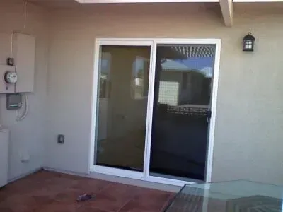 A patio with a sliding glass door and a table.