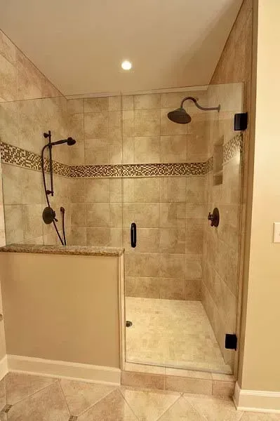 A bathroom with a walk in shower with a glass door.