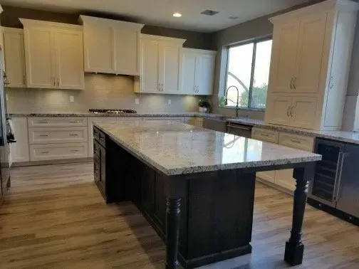 A kitchen with white cabinets and a large island in the middle.