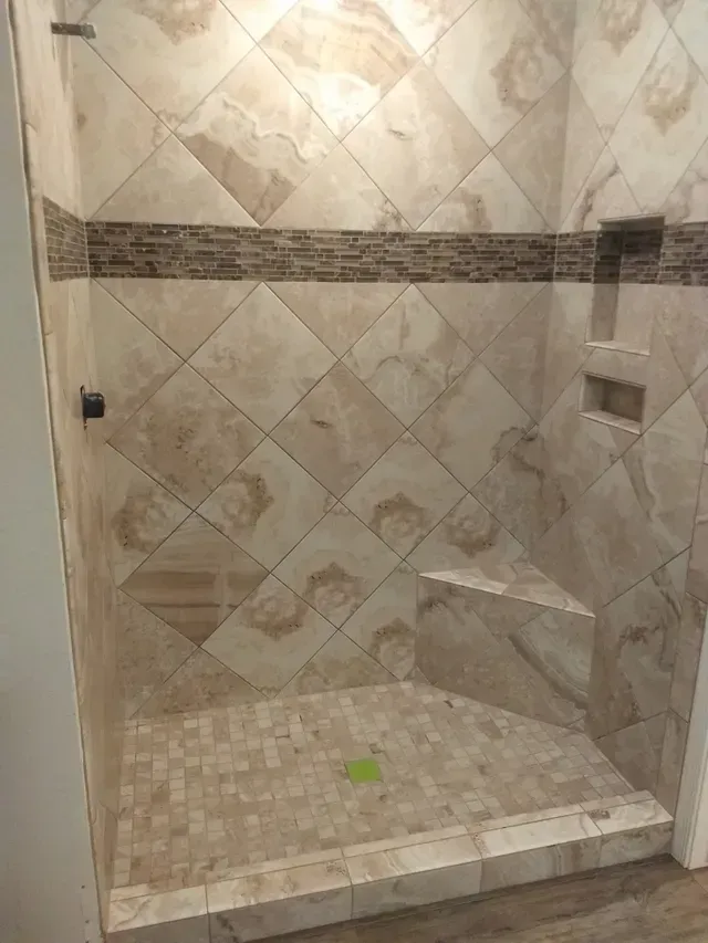 A bathroom with a walk in shower with tile walls and a glass door.