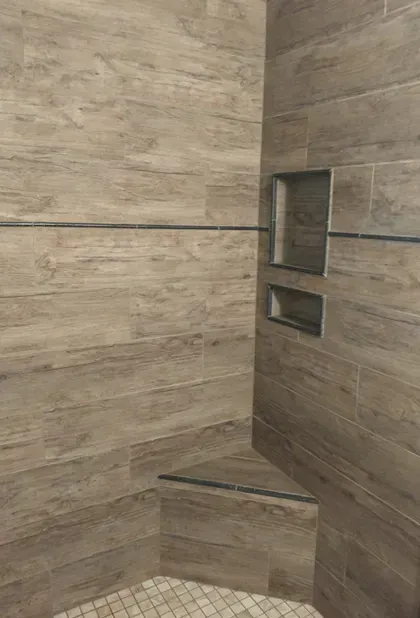 A shower with wooden tiles and a glass shelf.