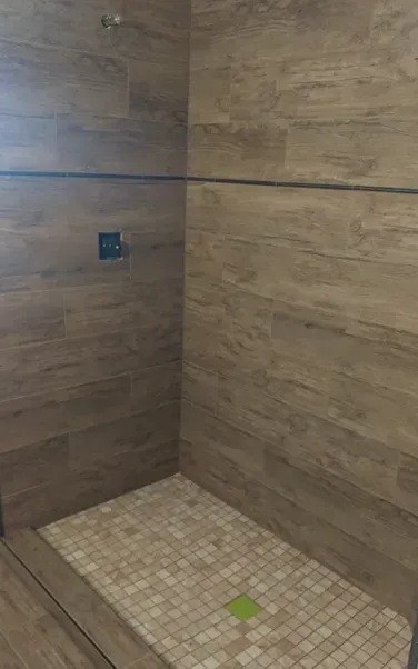 A walk in shower with wooden walls and a tiled floor.