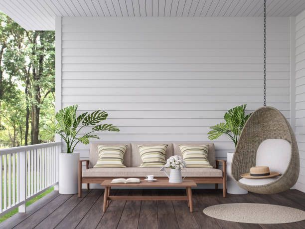 A porch with a couch , chair , table and potted plants.
