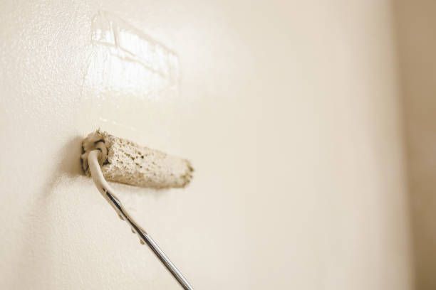 A paint roller is being used to paint a wall.