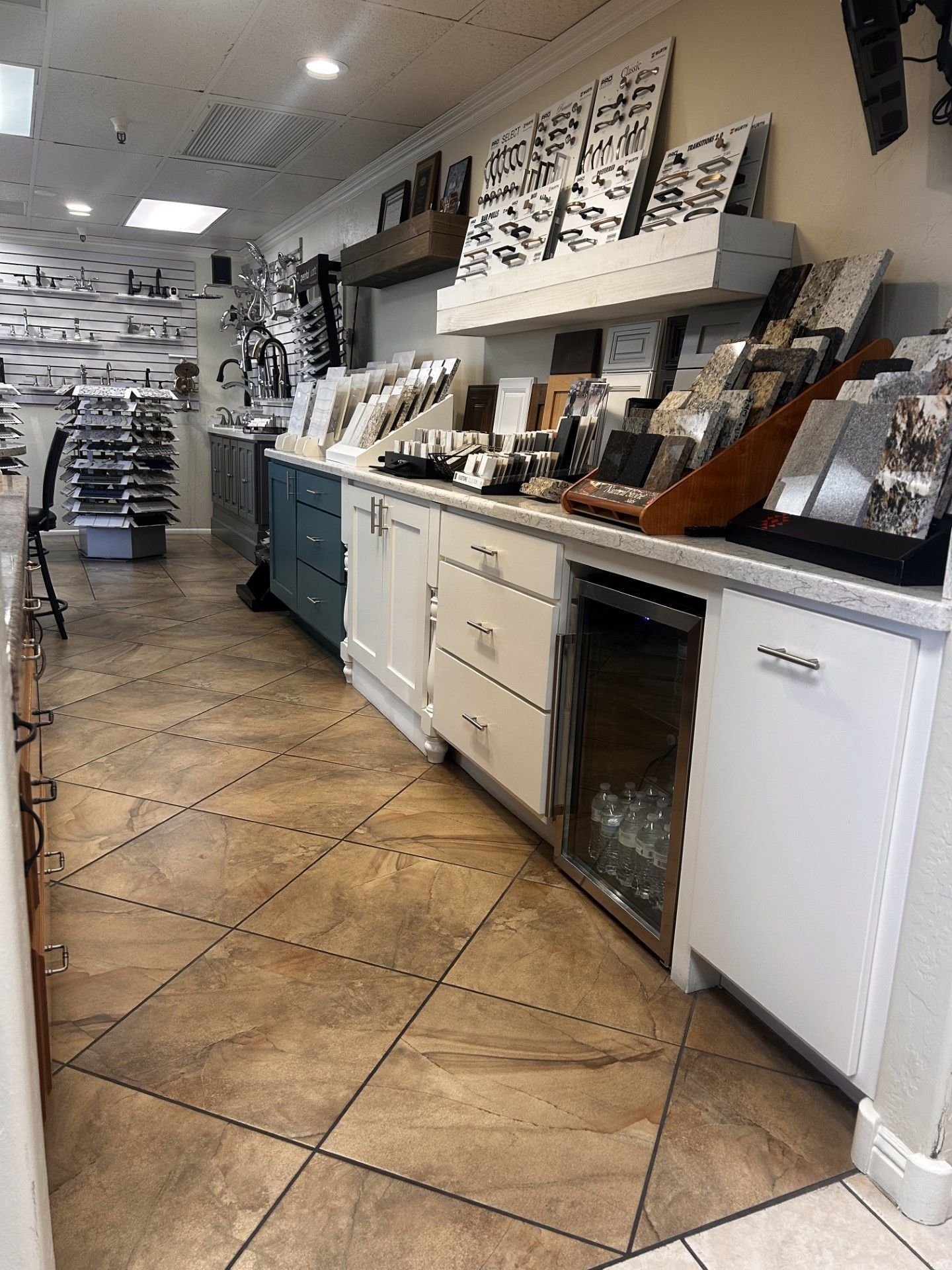 Interior of a showroom with cabinets, countertops, and samples of tiles and finishes.